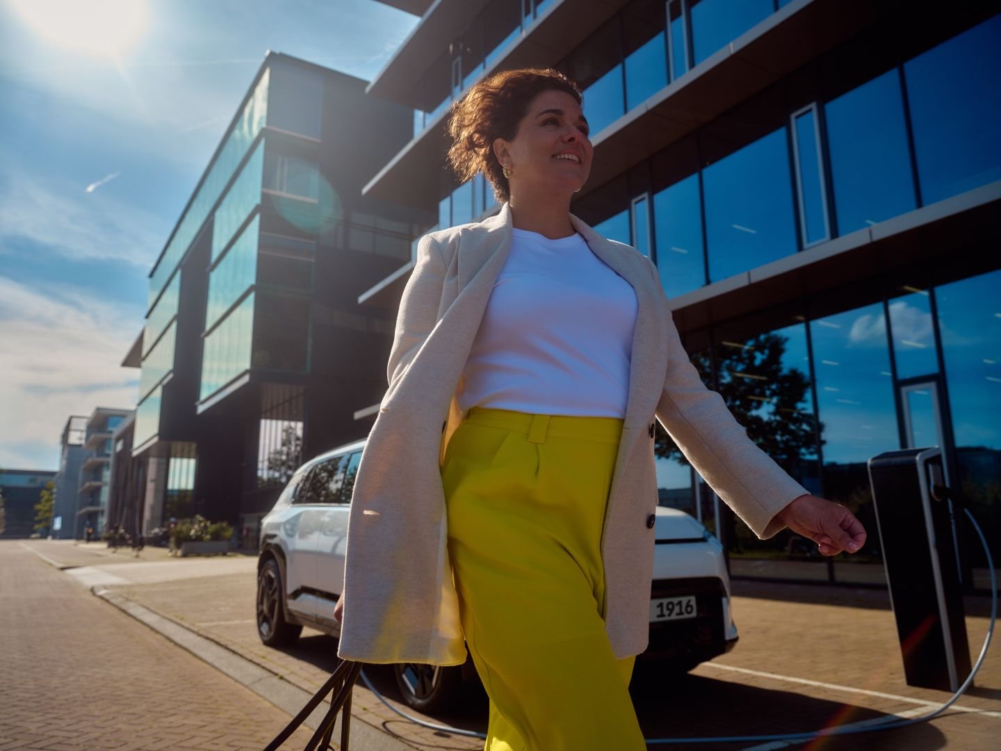 Woman walking in front of her car on a city street, Athlon Car Lease shoot in Amsterdam