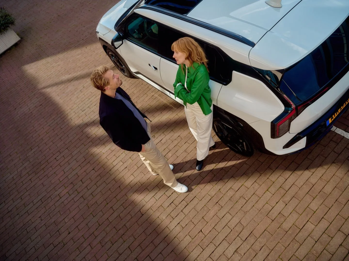 Man and woman talking next to a car in a business setting, Athlon Car Lease shoot in Amsterdam