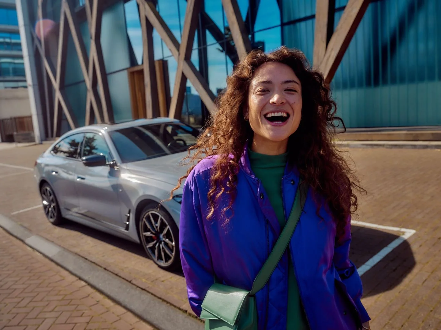 Woman smiling in an urban setting, car in the background, Athlon Car Lease shoot in Amsterdam