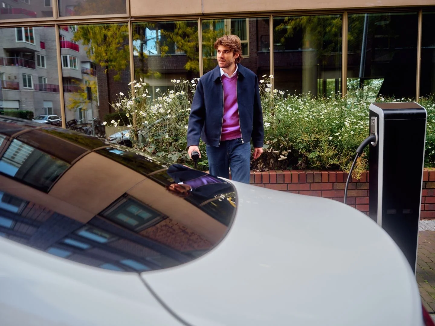 Man waiting by his car at a charging station, Athlon Car Lease shoot in Amsterdam