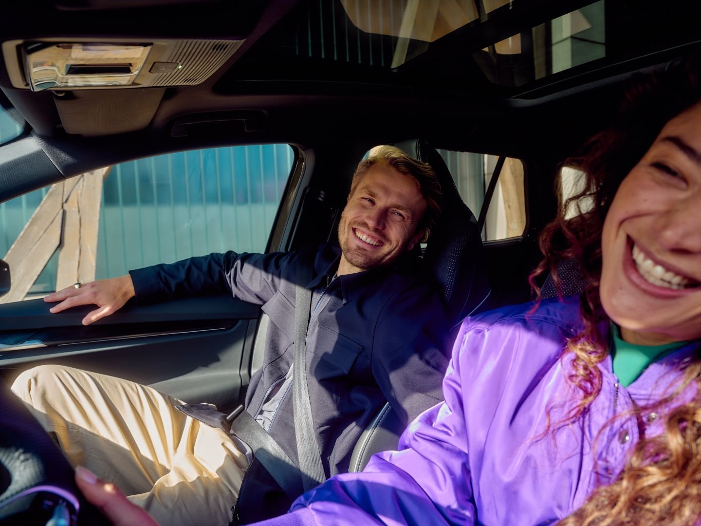 Woman driving and laughing with her passenger, Athlon Car Lease shoot in Amsterdam