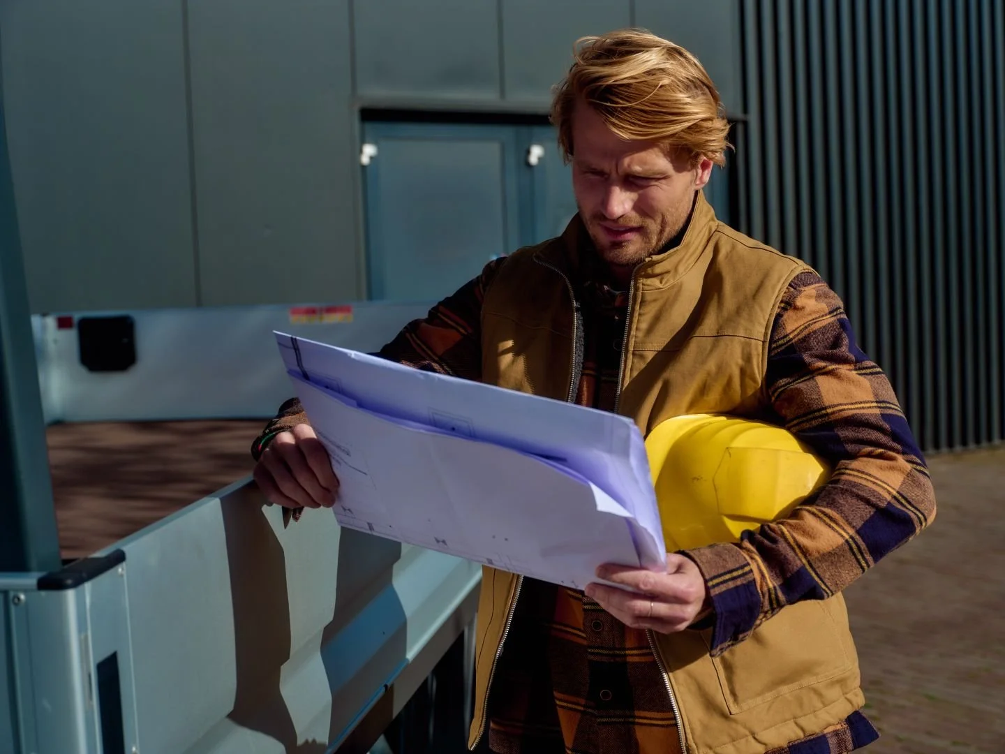 Builder in a yellow hard hat checking plans next to a van, Athlon Car Lease shoot in Amsterdam