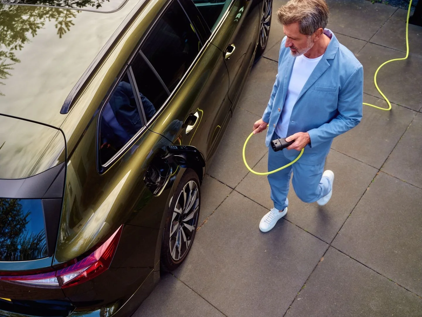 Man plugging his electric car into a home charger, Athlon Car Lease shoot in Amsterdam