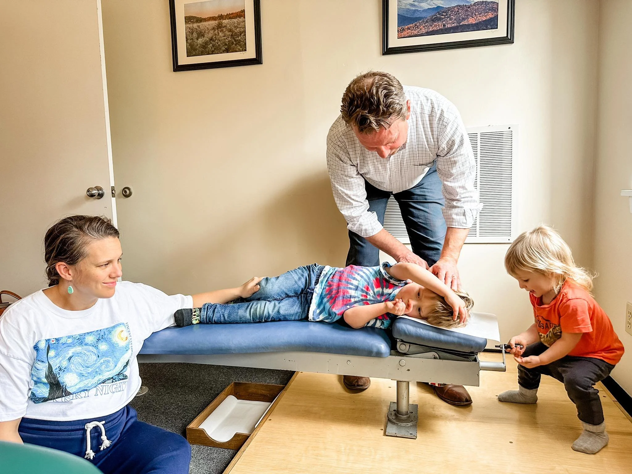 hiropractor performing a gentle alignment on a child with parent and sibling nearby in Vermont