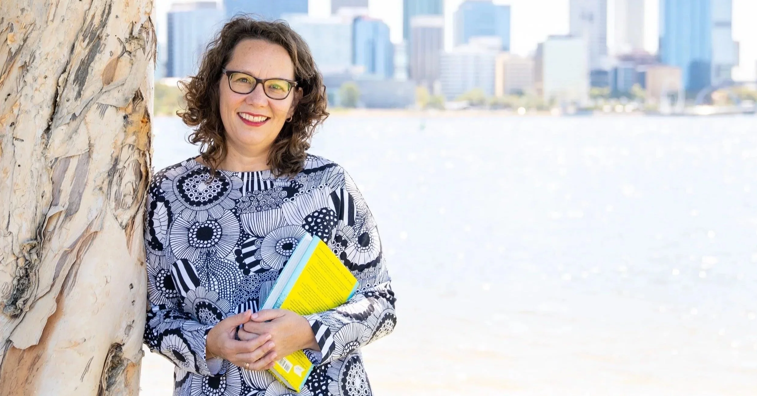 Portrait of Rachael Bernstone, founder of Sounds Like Design, with the Perth city skyline in the background