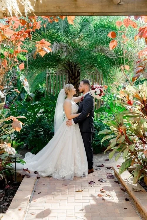 Couple under floral arch in tropical garden at wedding venue near Leesburg Florida