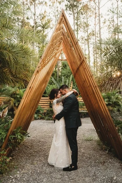 Couple kissing under wooden arch in forest at wedding venue near Land O Lakes Florida