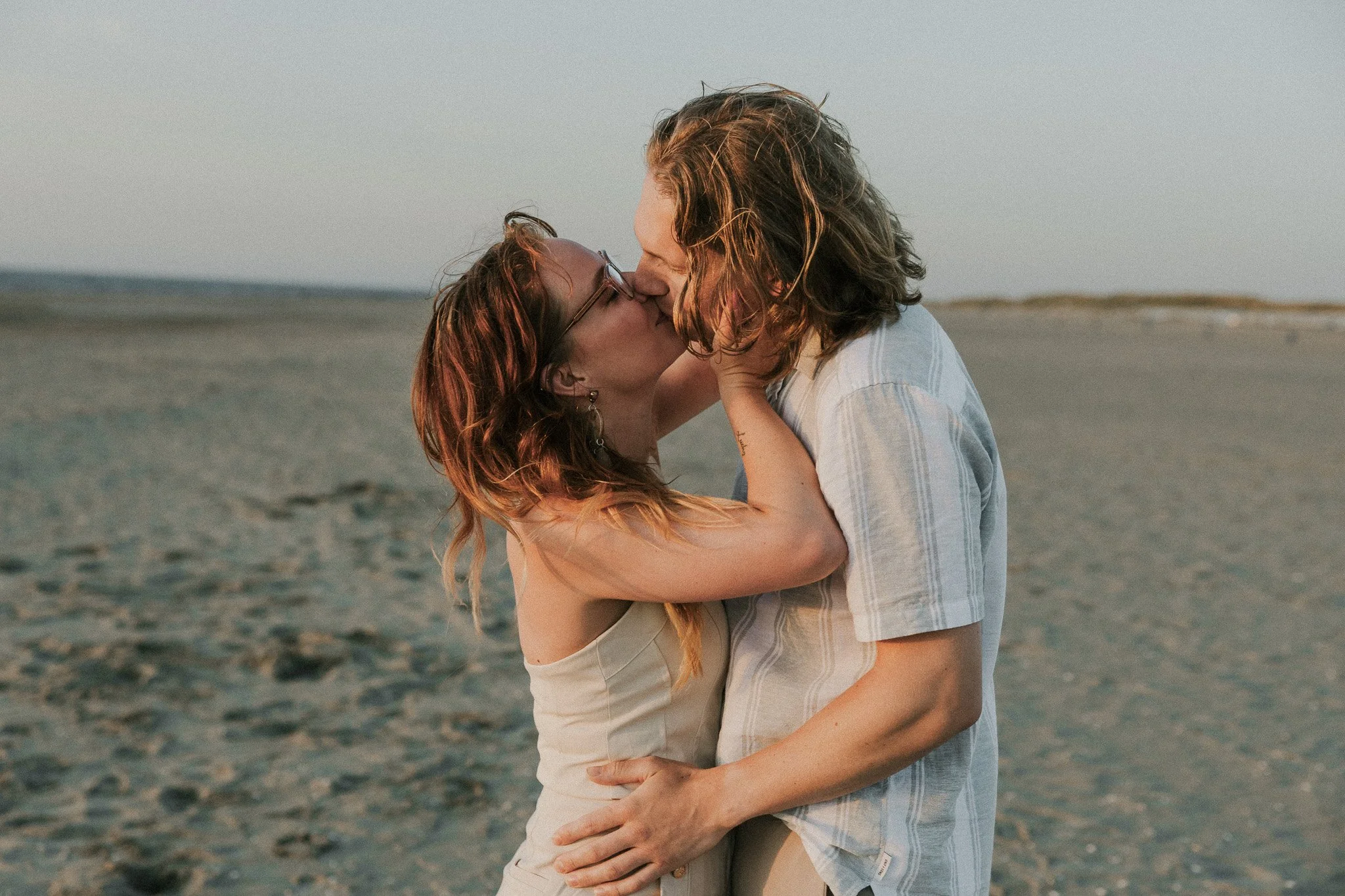 Een koppel kust elkaar op het strand tijdens zonsondergang