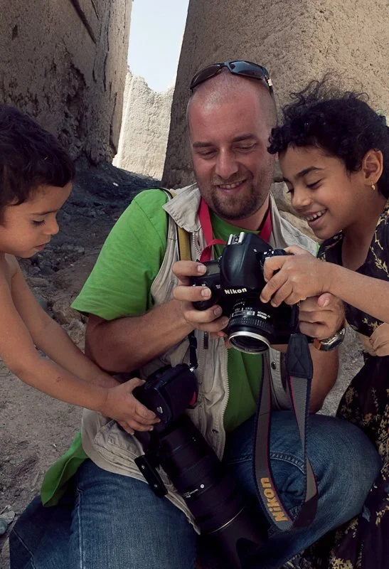 A man and two young girls looking at a camera together, smiling and enjoying an outdoor moment.