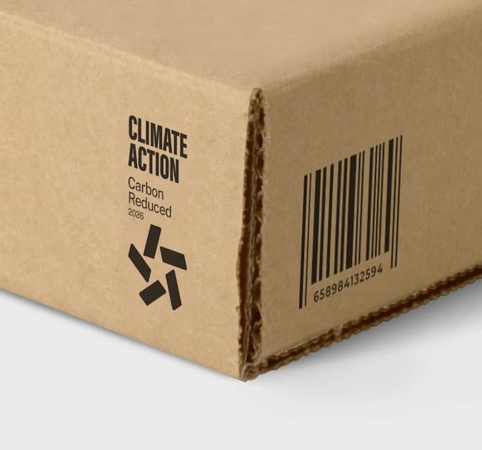 Close-up of a cardboard box with a climate action message about reducing carbon emissions by 2028, barcode, and recycling symbol.