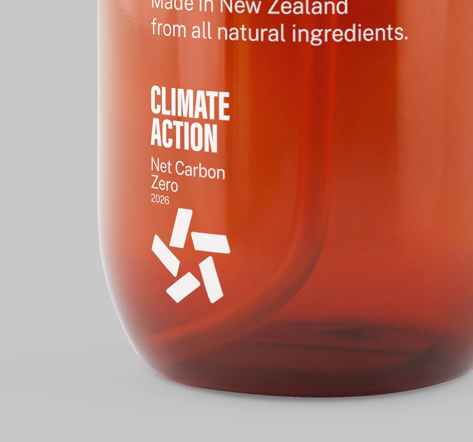 Close-up of a product label celebrating climate action, net zero carbon by 2026, made in New Zealand from all natural ingredients, with a red background and a recycling symbol.