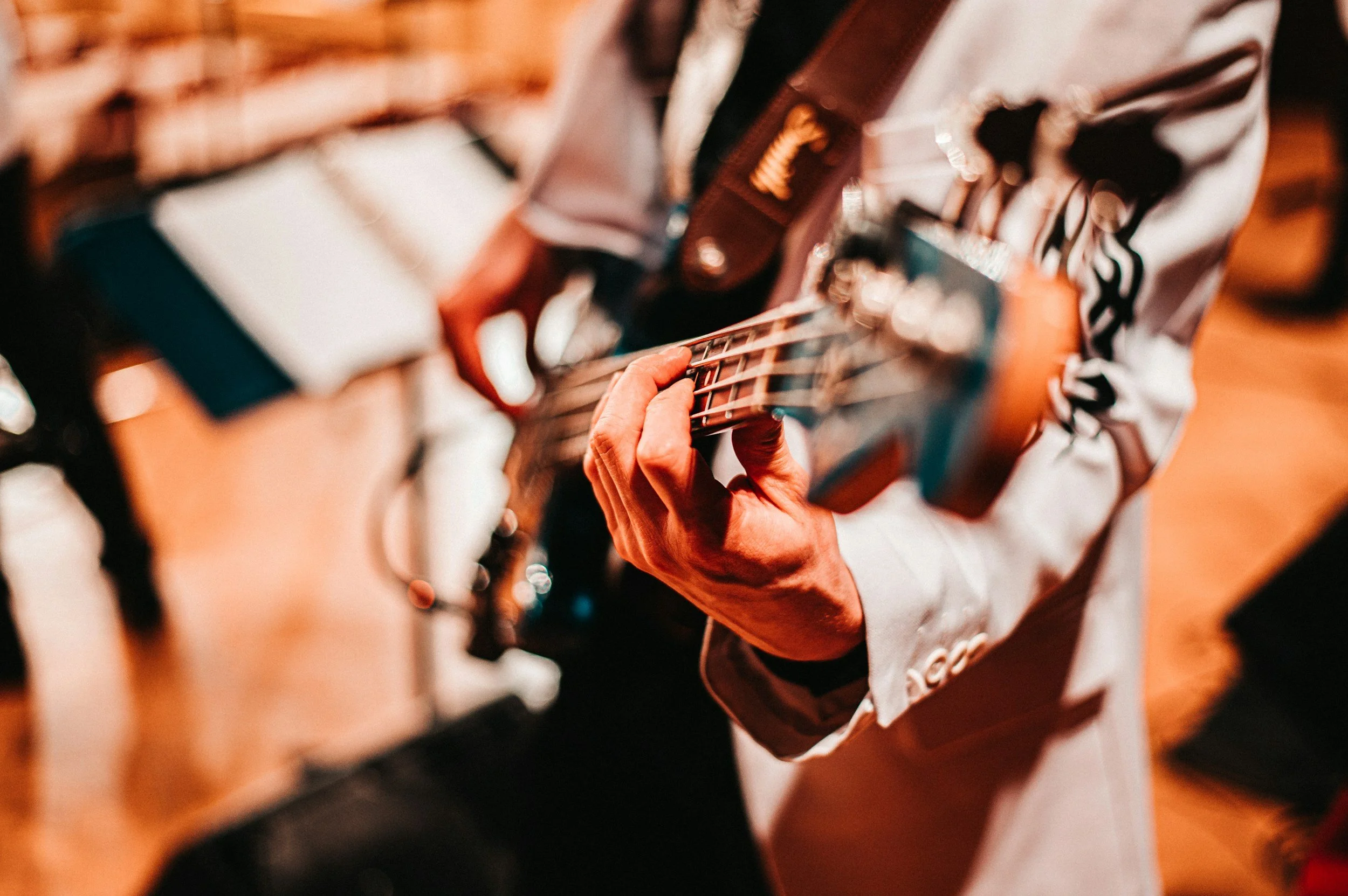 Close-up of a person wearing a white jacket playing an acoustic guitar.