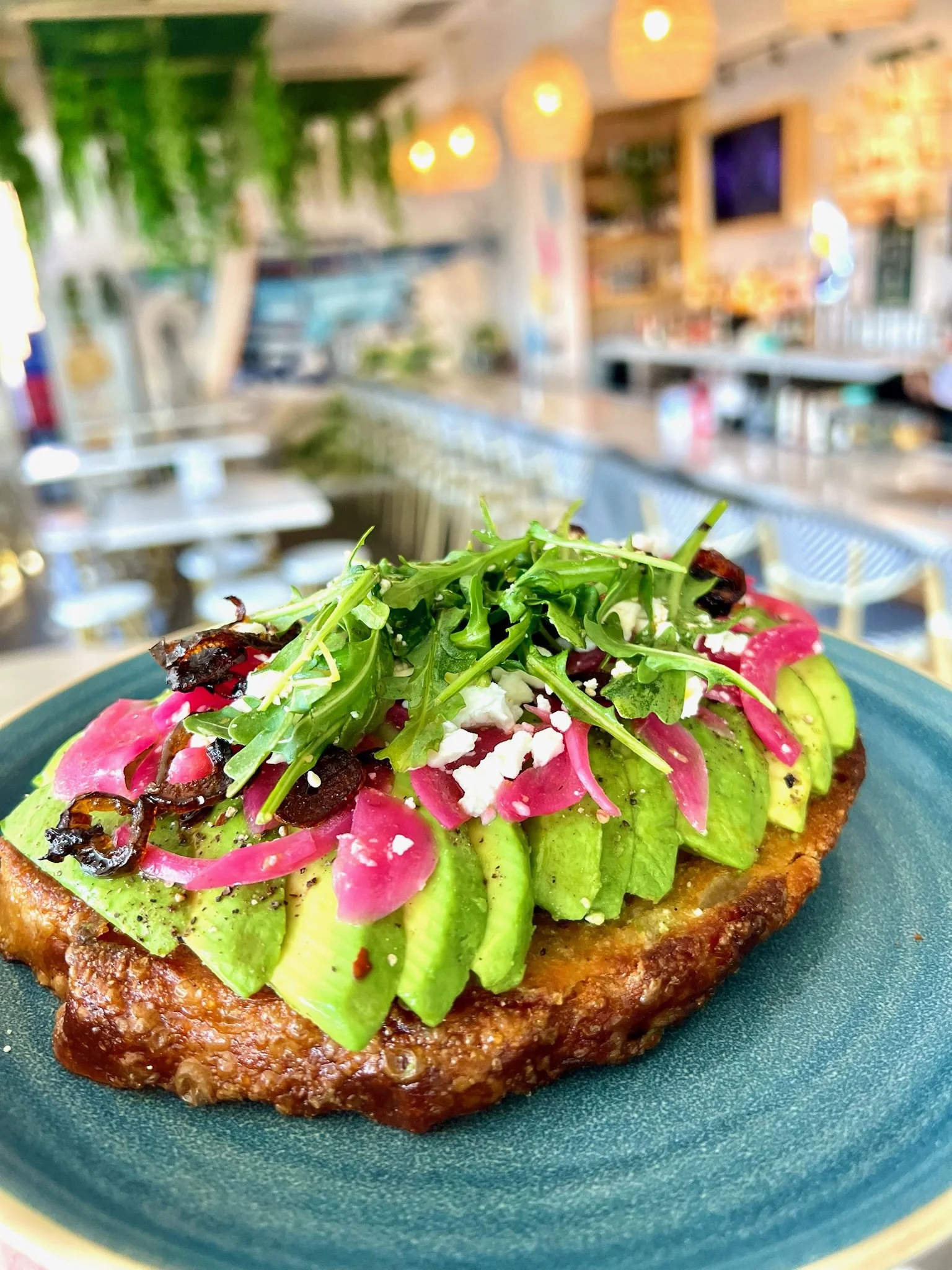 NIKI AVOCADO TOAST sliced avocado, crumbled feta, pickled red onions, chili crisp oil, lemon dressed arugula