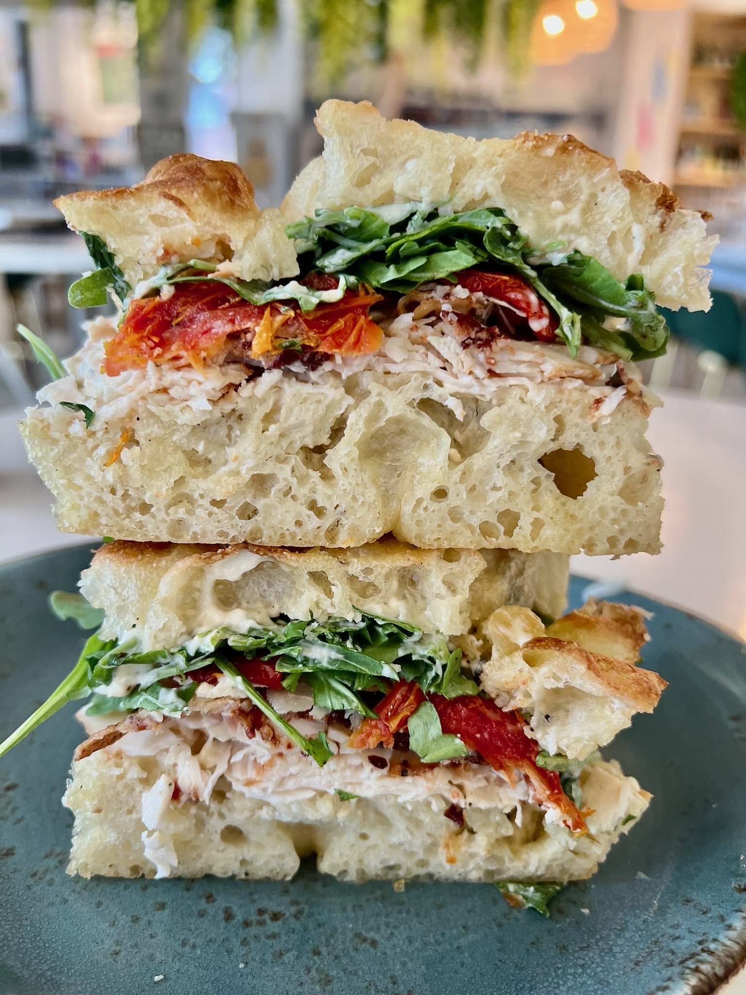 PETER PETER CAESAR CAESAR thinly sliced chicken, pancetta, sun dried tomato, arugula, shaved parmesan, caesar dressing on house focaccia
