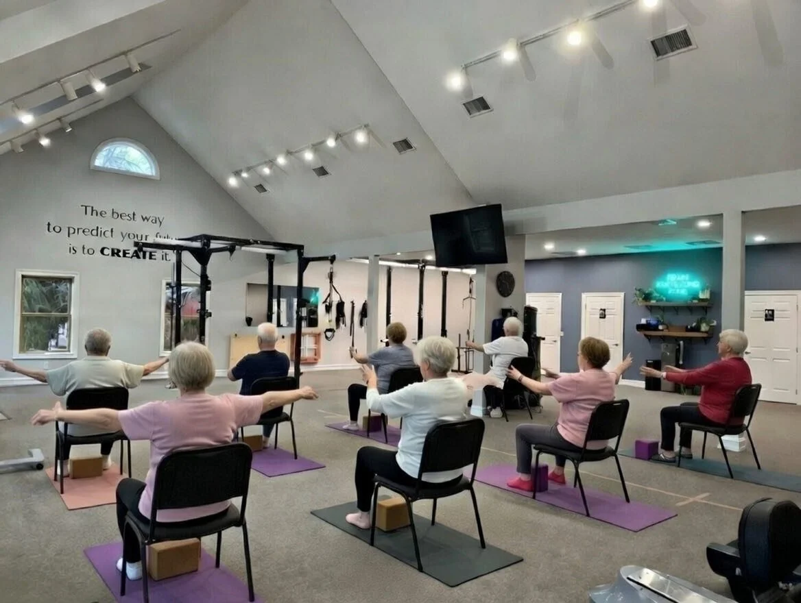Seated chair yoga participants with outstretched arms in therapy gym in Waynesville, Ohio.