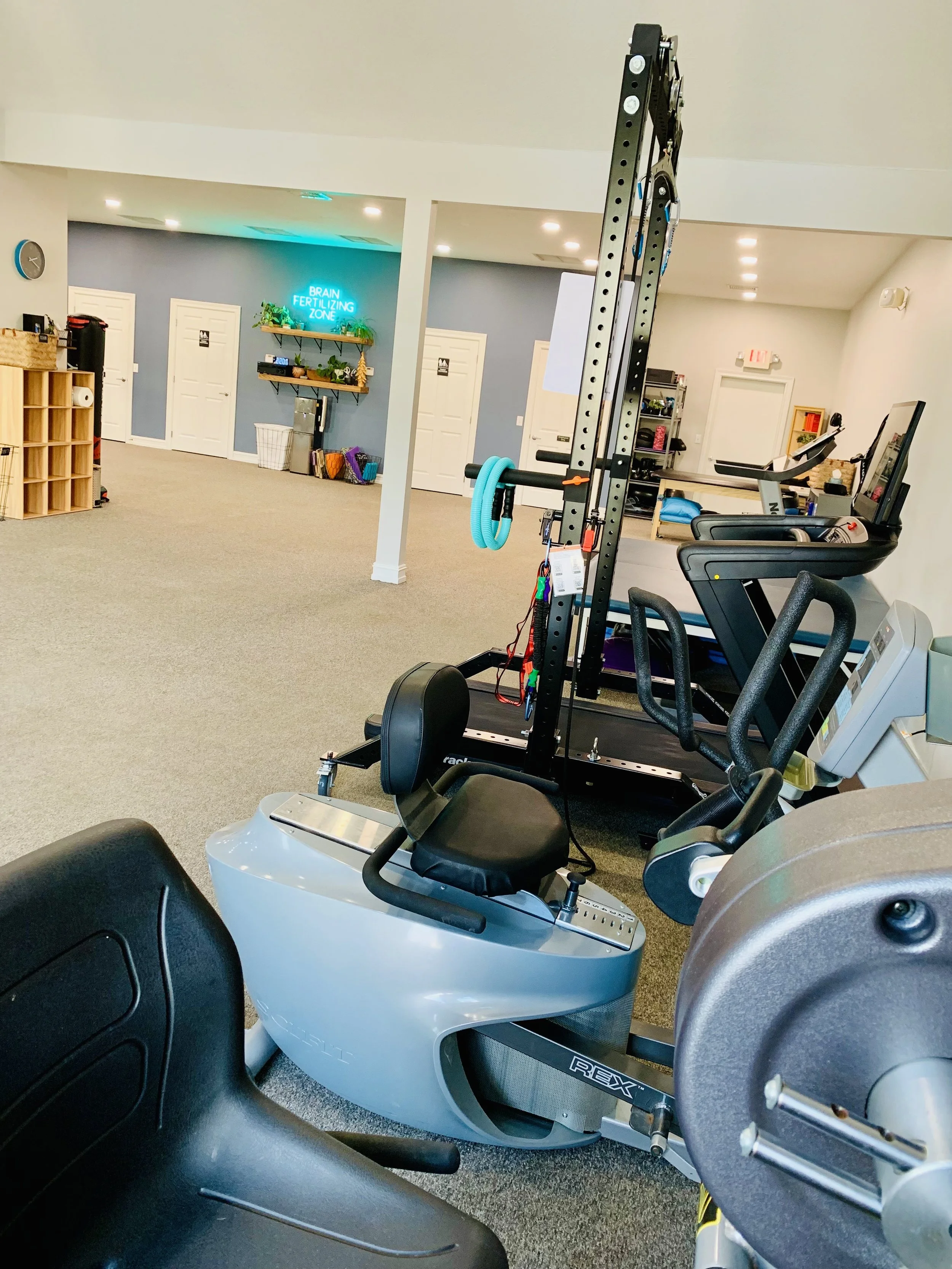 Cardio exercise clinic at Empower Balance gym with neon sign against blue wall in the background.