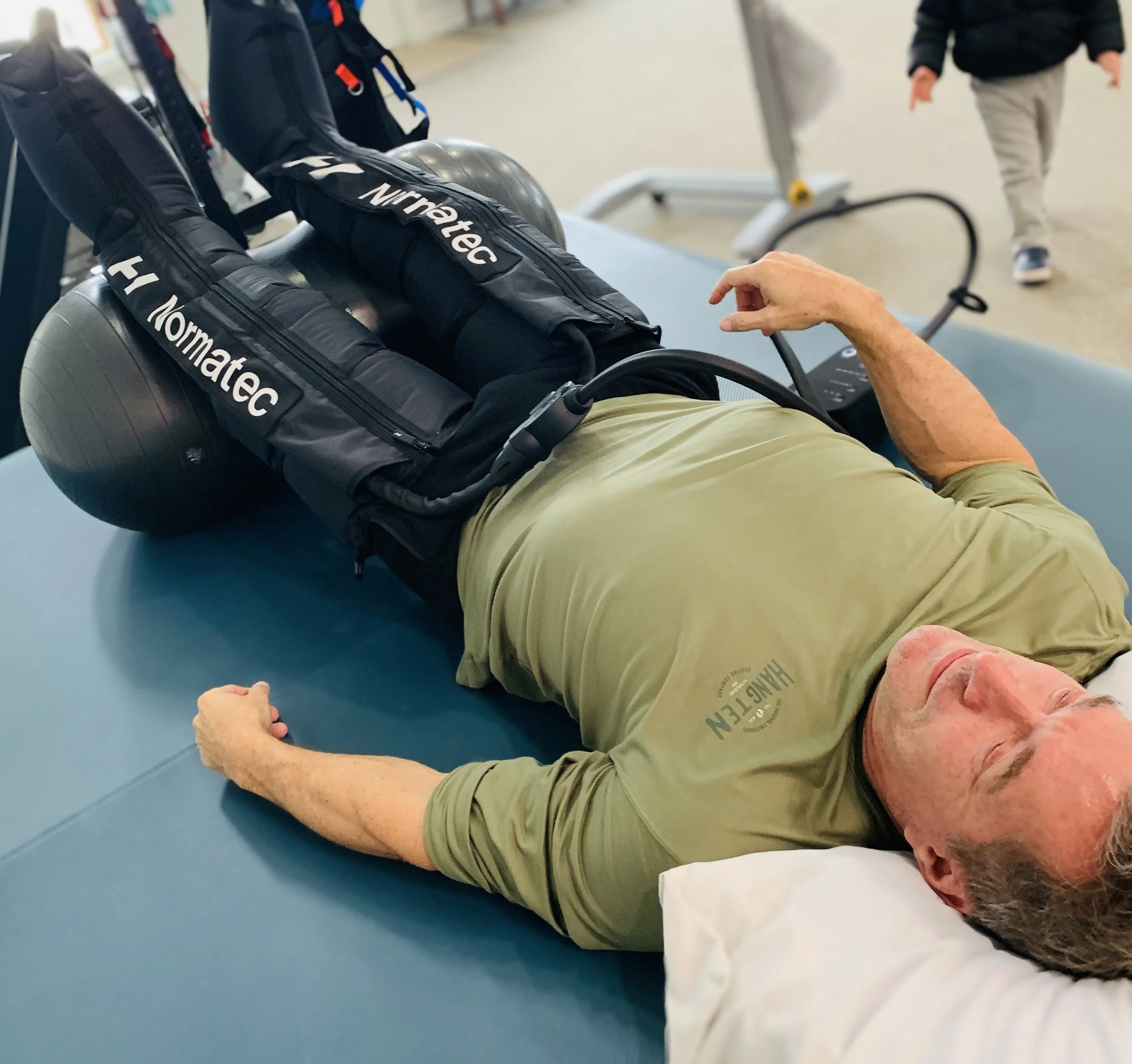 Man laying down with legs elevated on ball wearing compression therapy at Empower Balance in Waynesville.