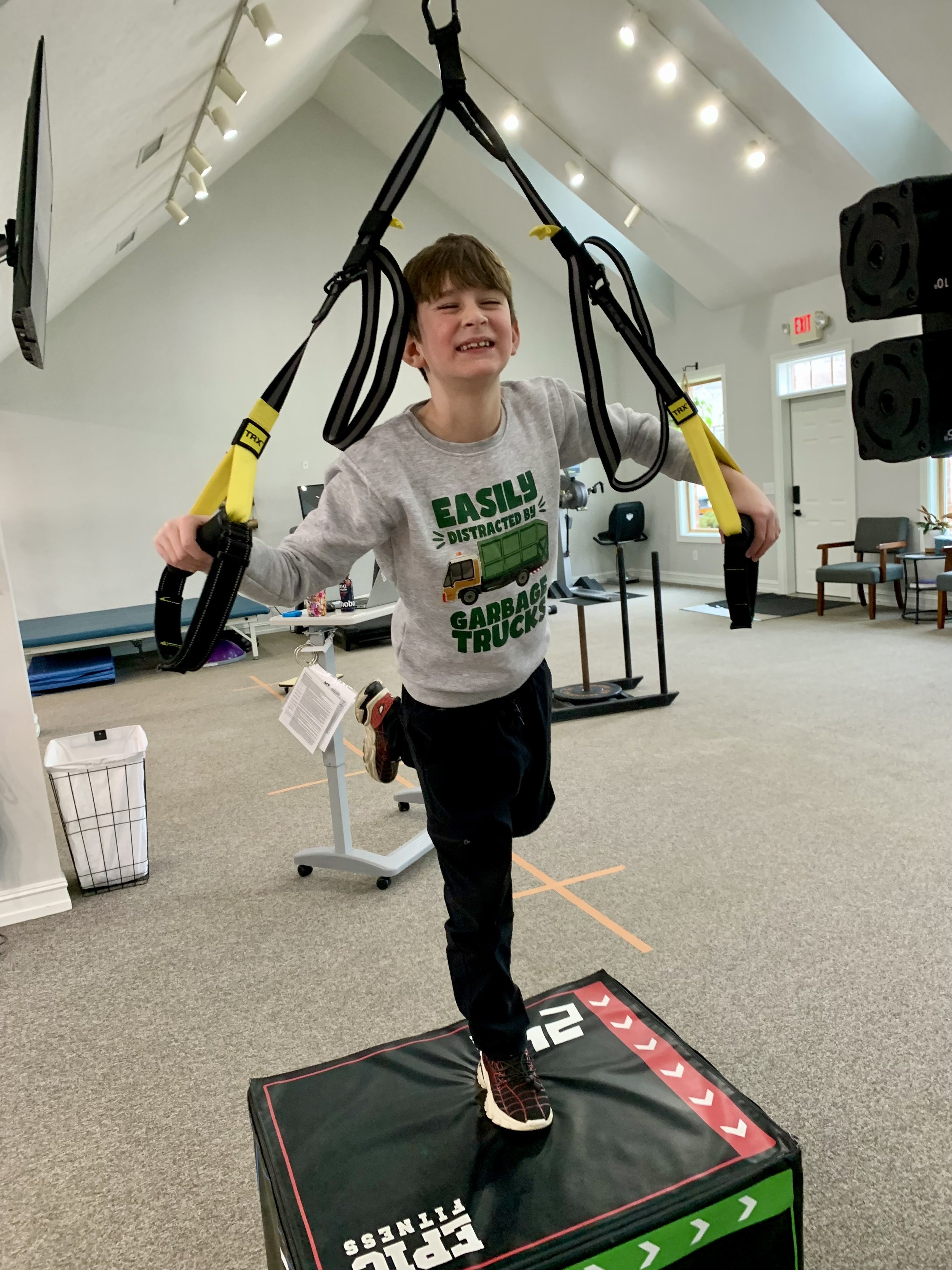 Smiling boy balancing on one leg with balance straps at Empower Balance.