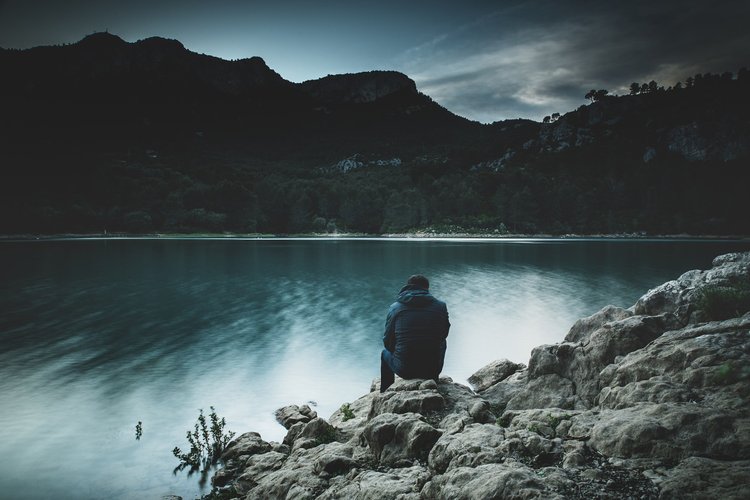A man standing calmly by a lake