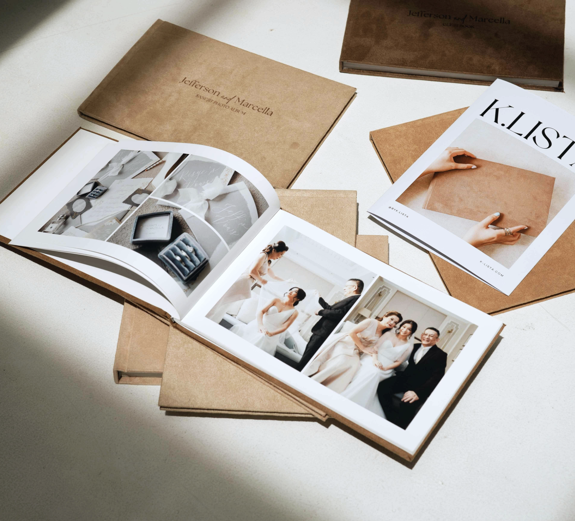 Open photo album with wedding pictures, surrounded by more albums and a magazine on a light surface.