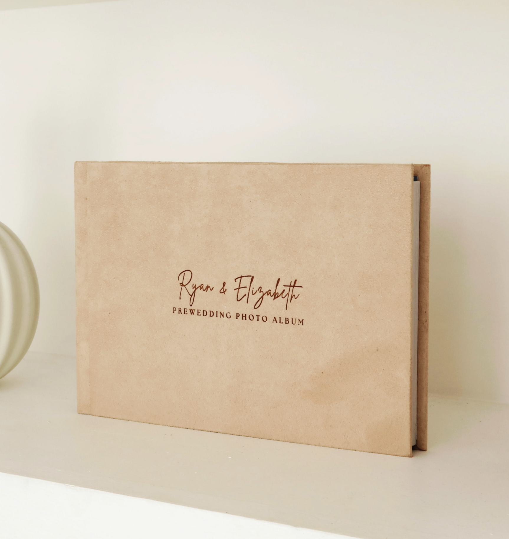 Beige prewedding photo album on shelf.