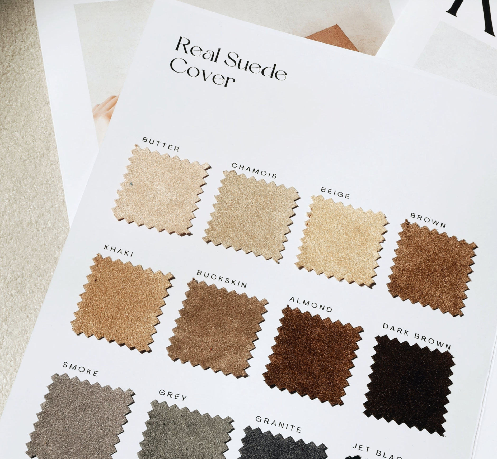 Swatch card displaying various shades of suede labeled butter, chamois, beige, brown, khaki, buckskin, almond, dark brown, smoke, grey, granite, and jet black.