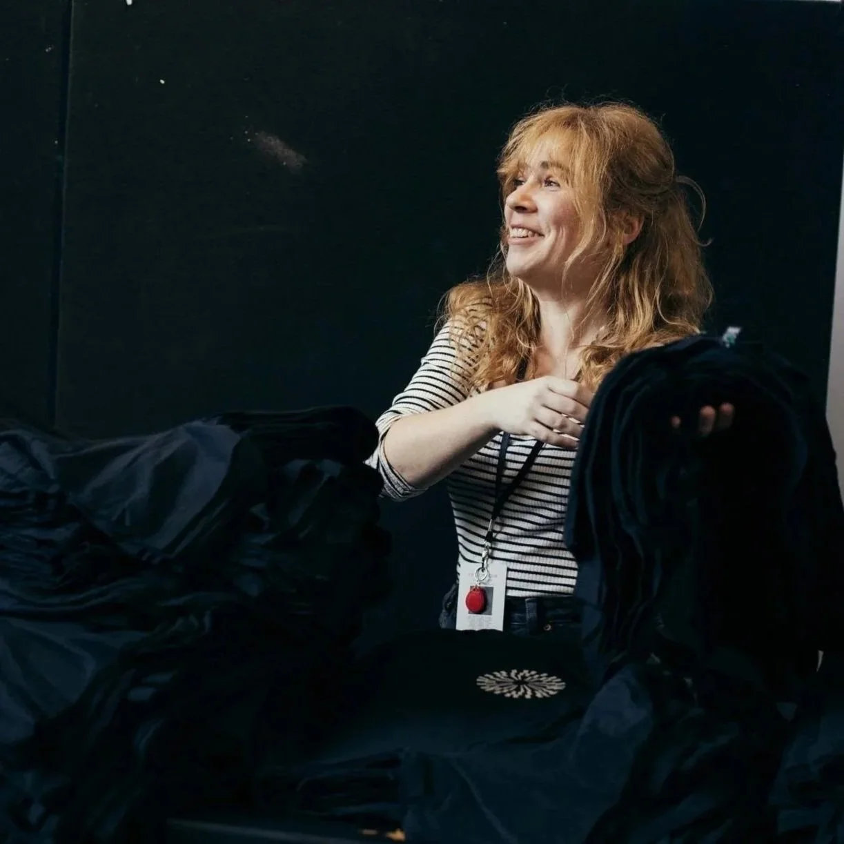 Pauline Bourdon sitting on the ground and laughing covered in black fabric.