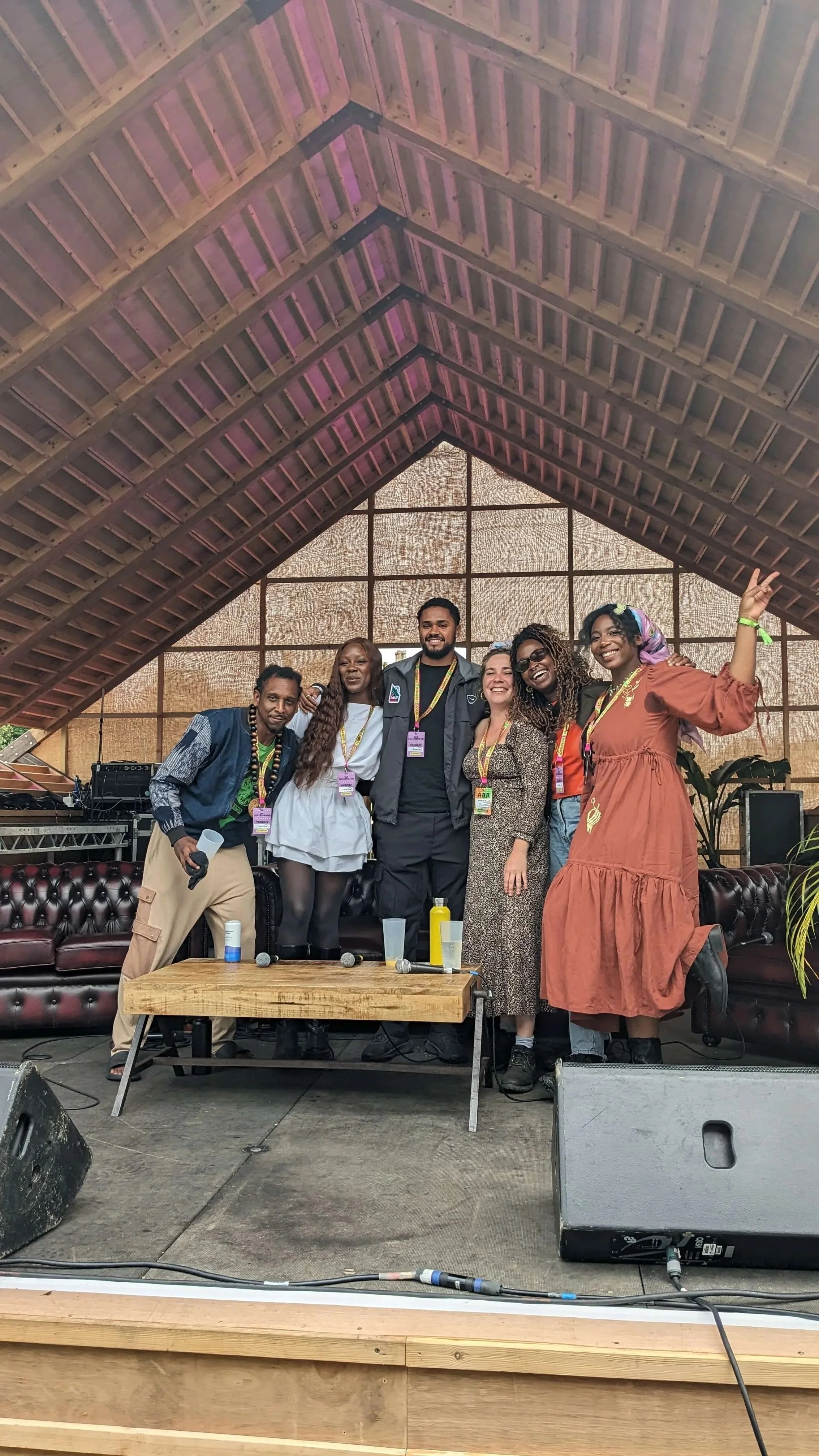 Group photo of six standing on stage, arm in arm and people smiling at the camera and smiling at the camera.