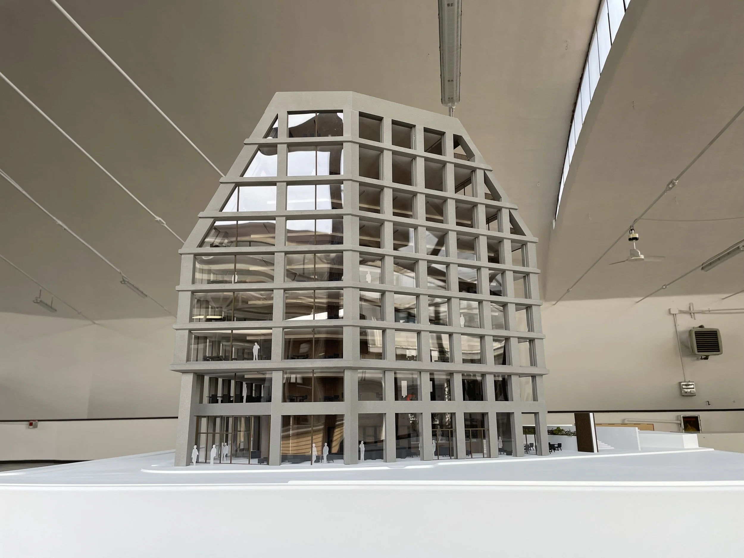 Modello architettonico di un edificio con forma a torre, dettagli in bianco, con più piani e una struttura aperta con molto spazio vetrato.