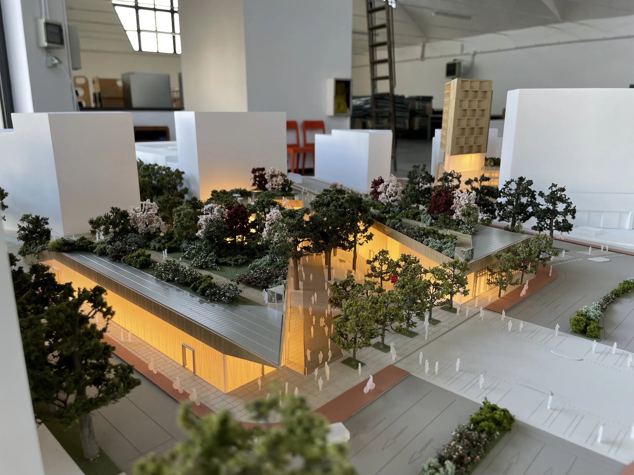 Modello di un complesso edilizio conificazione, piante e strutture illuminate, con alberi e persone in miniatura.