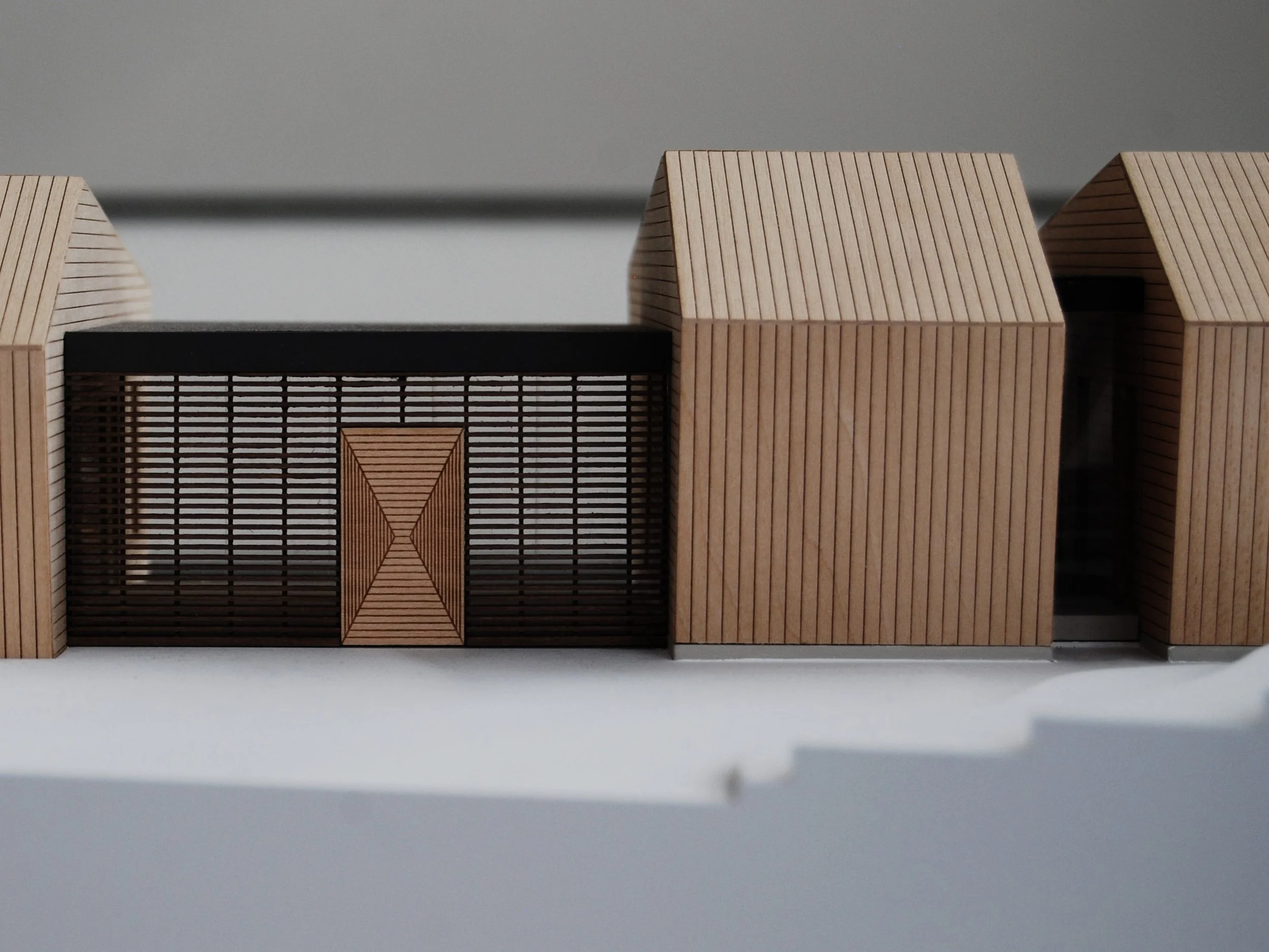 Modellino di edifici con strutture di legno e metallo, su sfondo bianco.