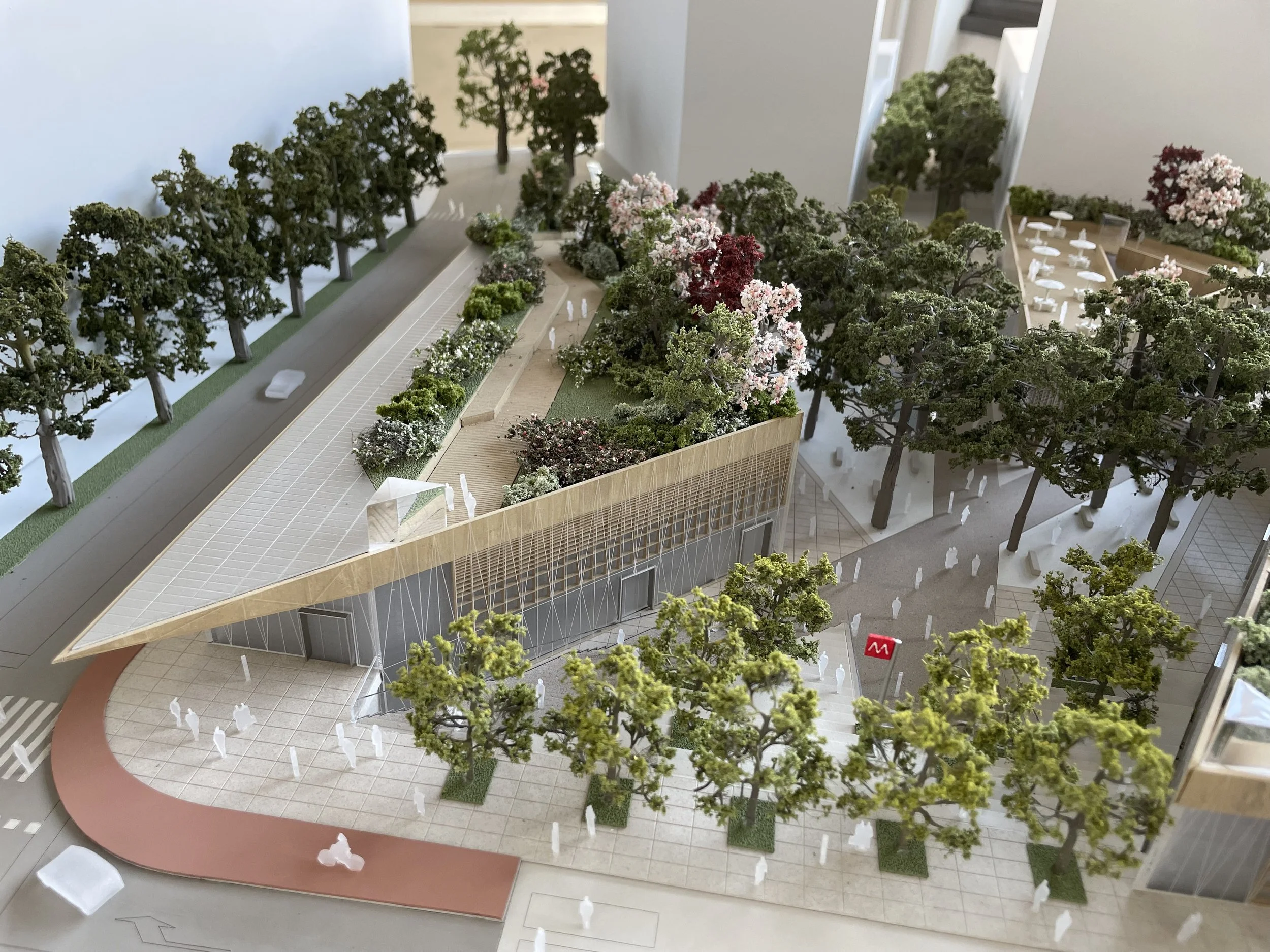 Modello di un parco urbano con alberi, panchine e spazi pedonali e un edificio in vetro.