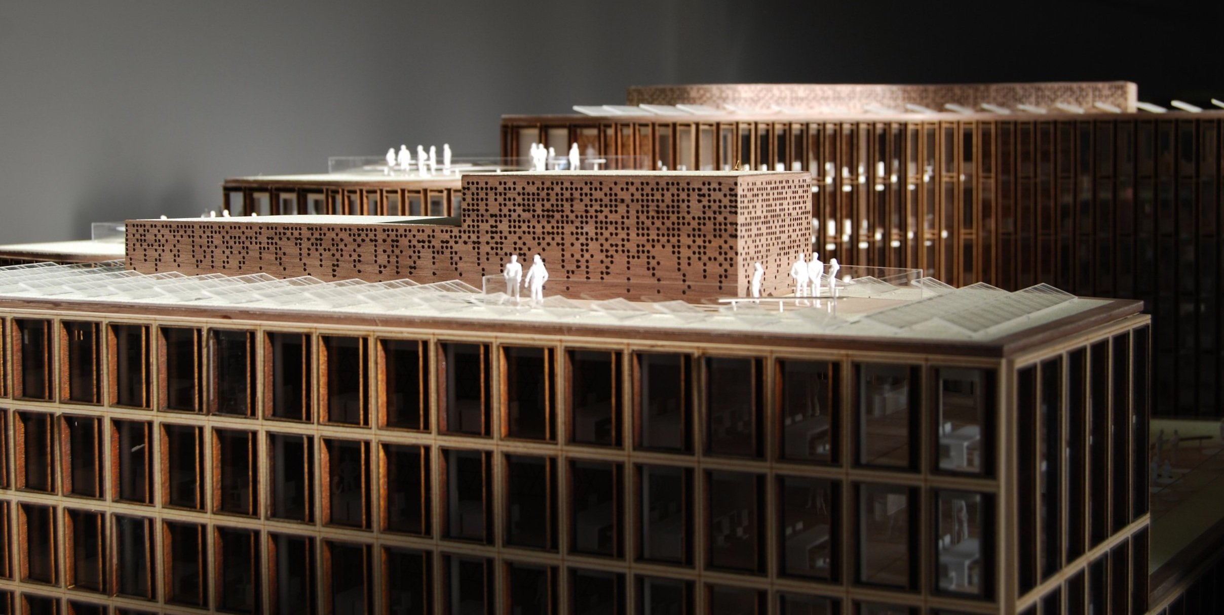 Modello architettonico di un complesso edilizio con edifici in legno e figure umane minute per scala.