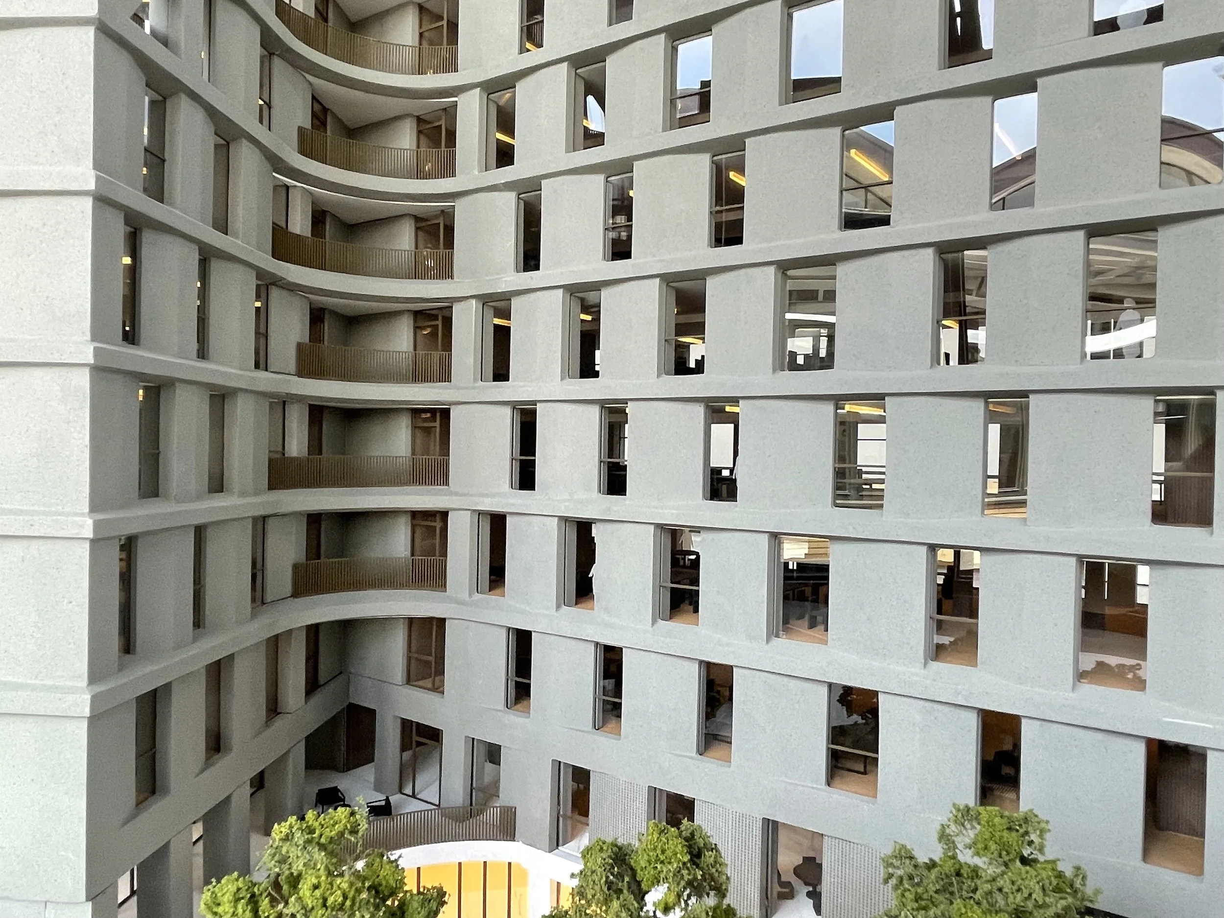 Un edificio moderno con varie finestre e balconi, viste dall'angolazione, con alcuni alberi in primo piano.