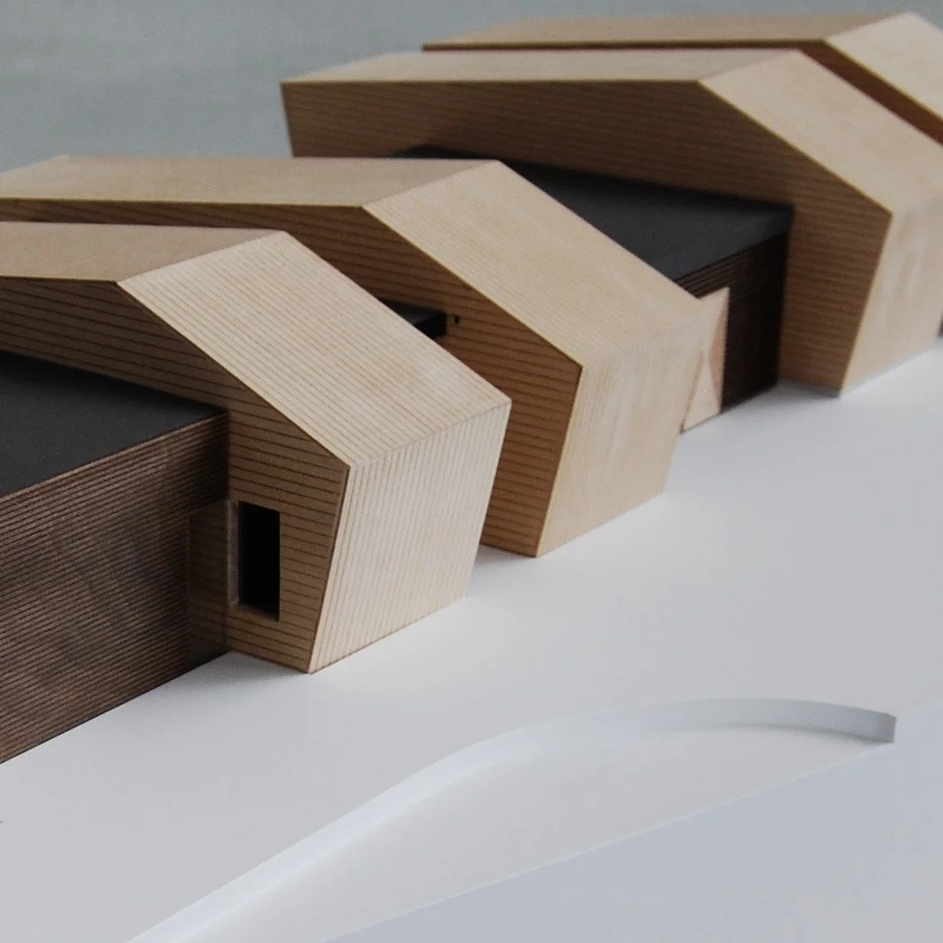 Modello architettonico con strutture di legno a forma angolare e fotografia zoomata.