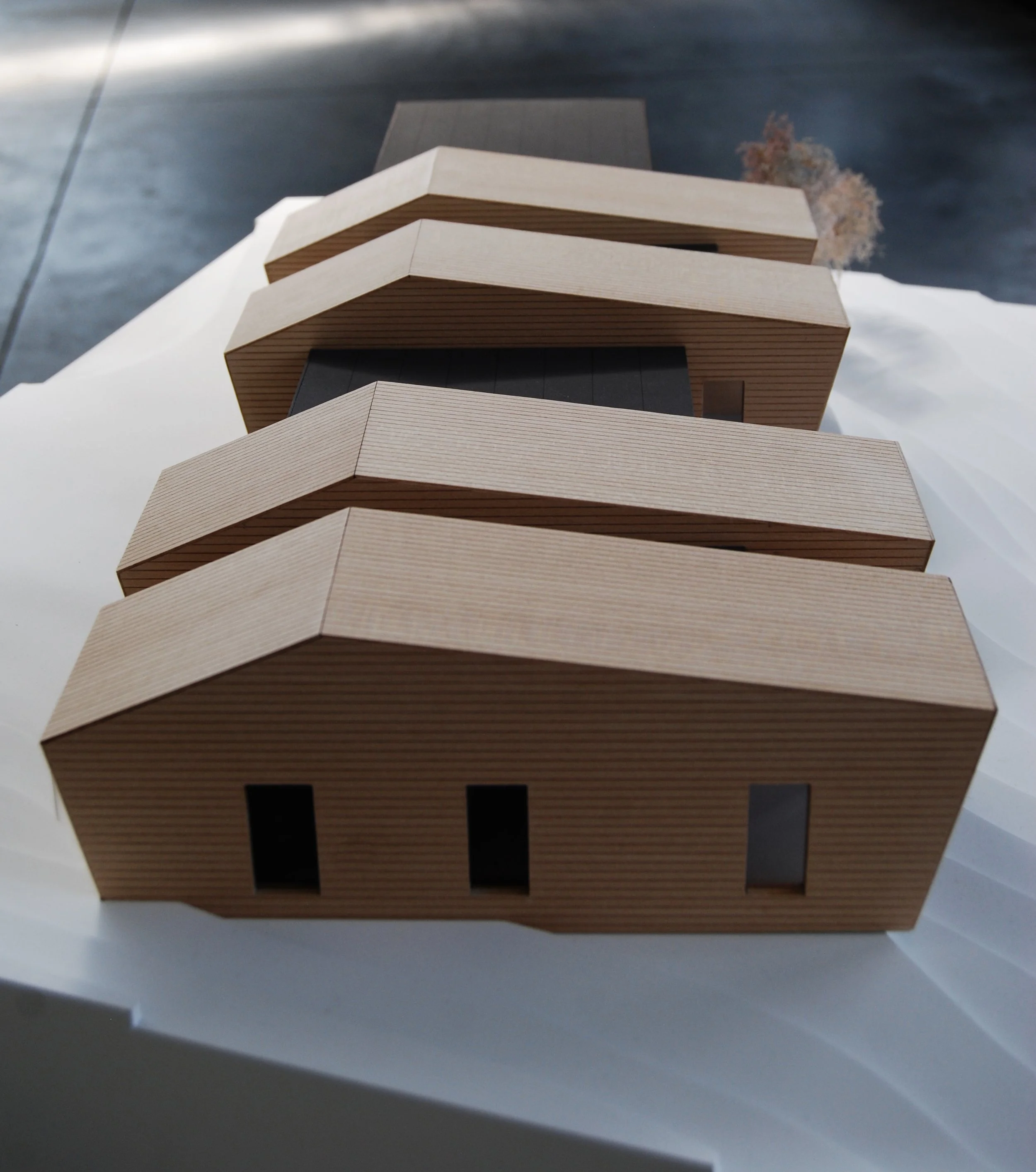 Modello di edificio moderno in legno con dettagli neri e grandi finestre, visto dall'alto.