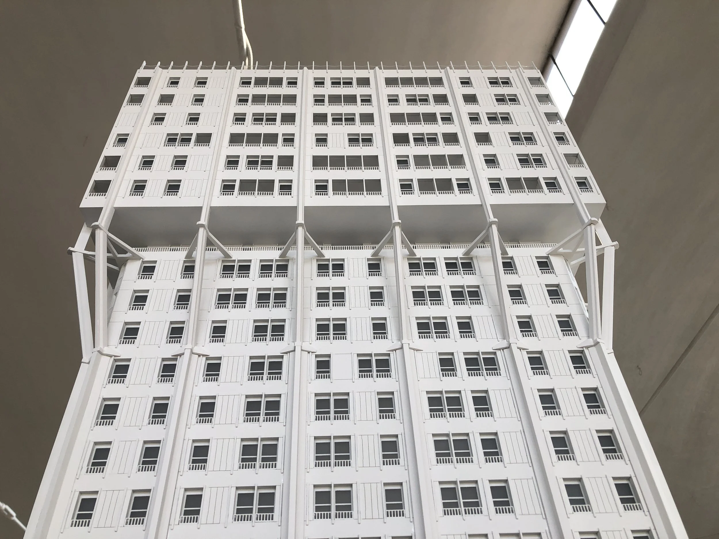 Modellino di un grattacielo bianco con molte finestre e balconcini, visibile da sotto con un angolo verso l'alto