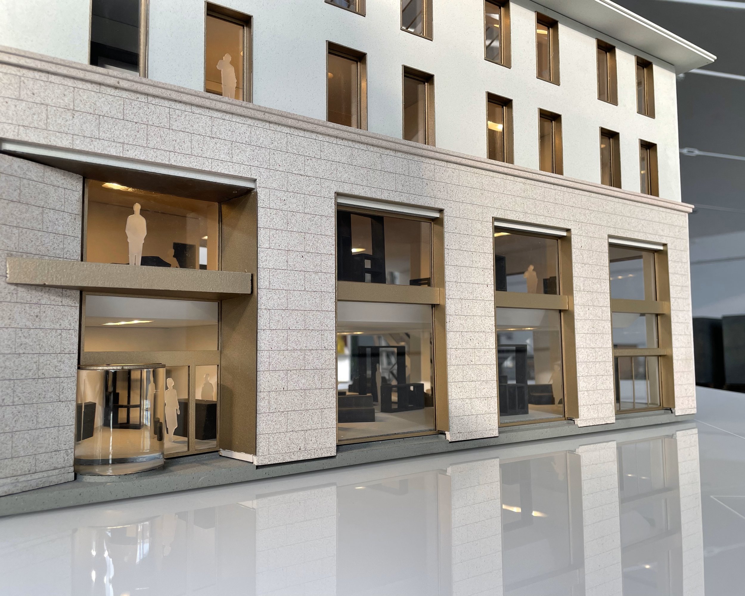 Modello in scala di un edificio moderno con finestre e figure umane stilizzate all’interno.