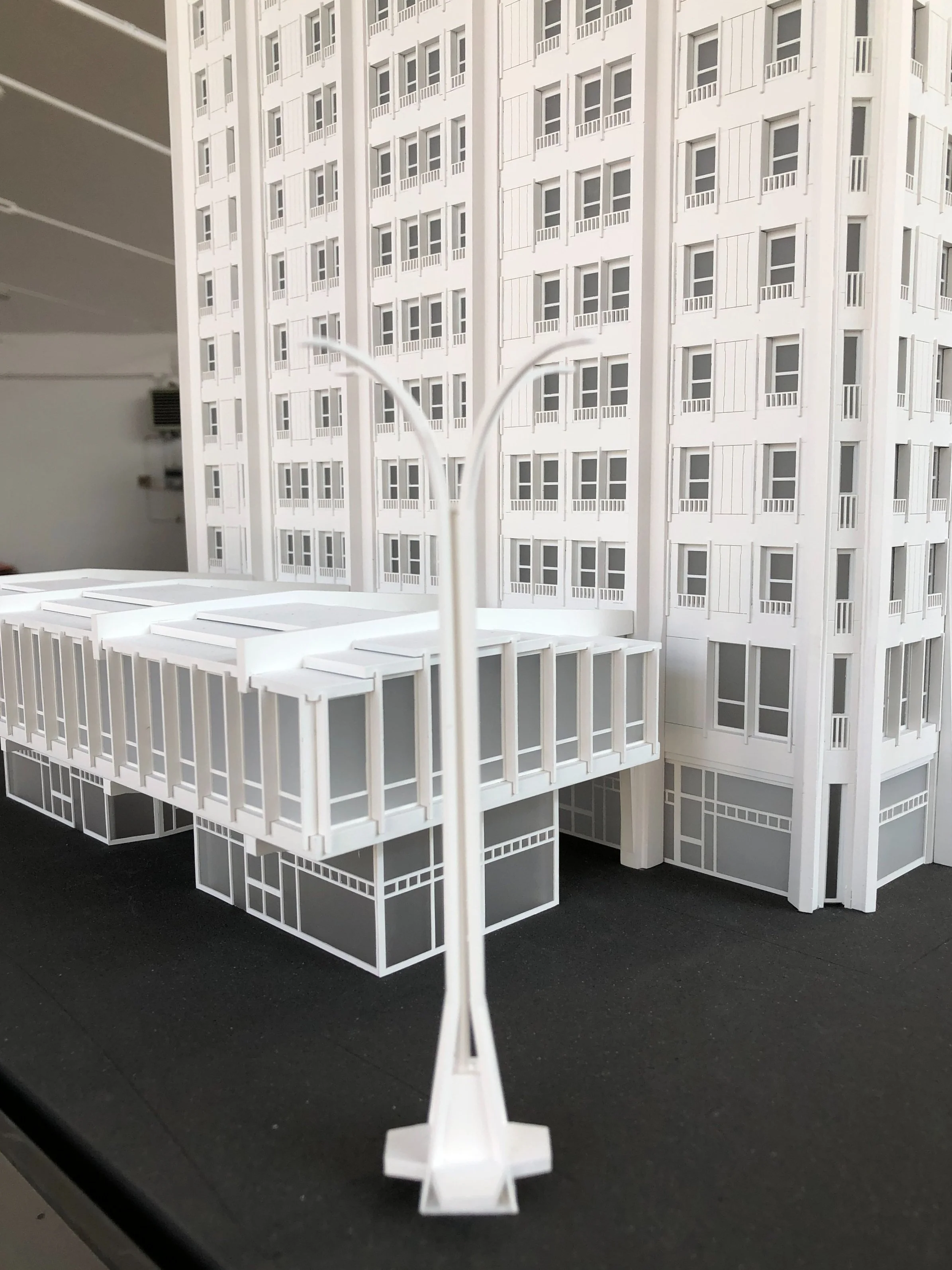 Modello in scala di un edificio con numerosi piani e balconi, visualizzato da un punto di vista ravvicinato con un'attenzione particolare a una struttura in primo piano. L'immagine è molto dettagliata e rappresenta una replica architettonica.