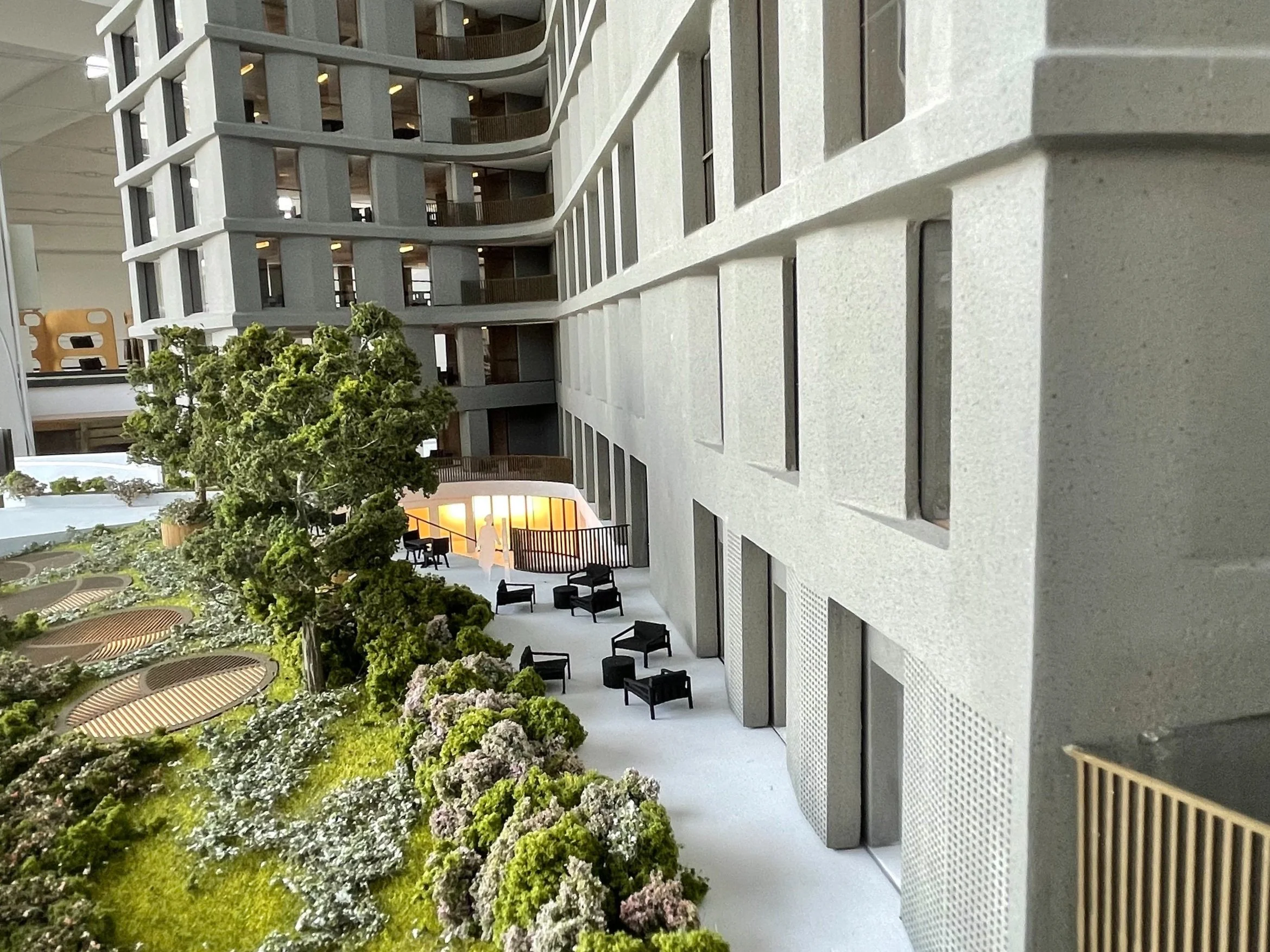 Veduta di un cortile interno di un edificio moderno con panchine, sedie e piante.
