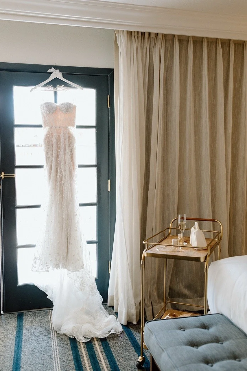 A wedding dress hanging on a hanger on the back of a door in a hotel room