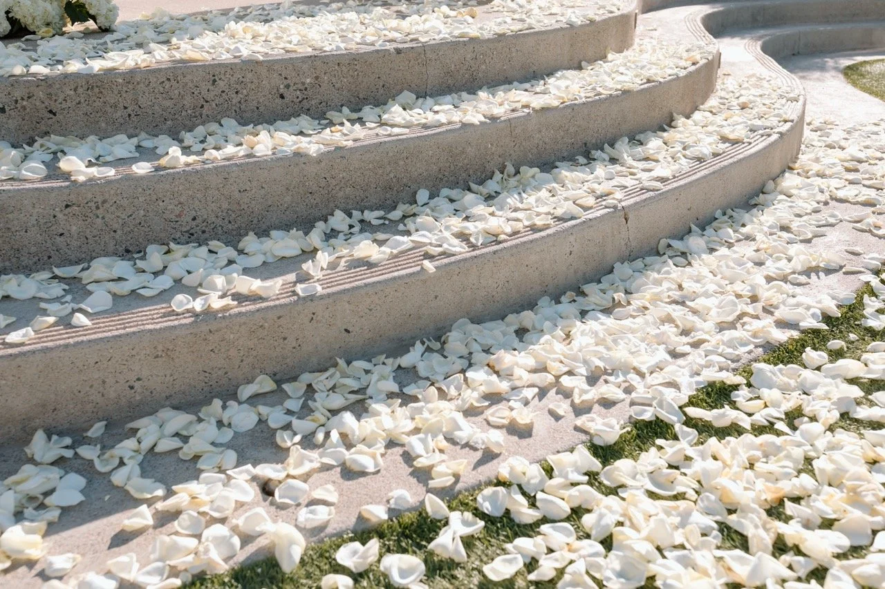 Ceremonial steps covered with white flower petals leading to an outdoor ceremony area.