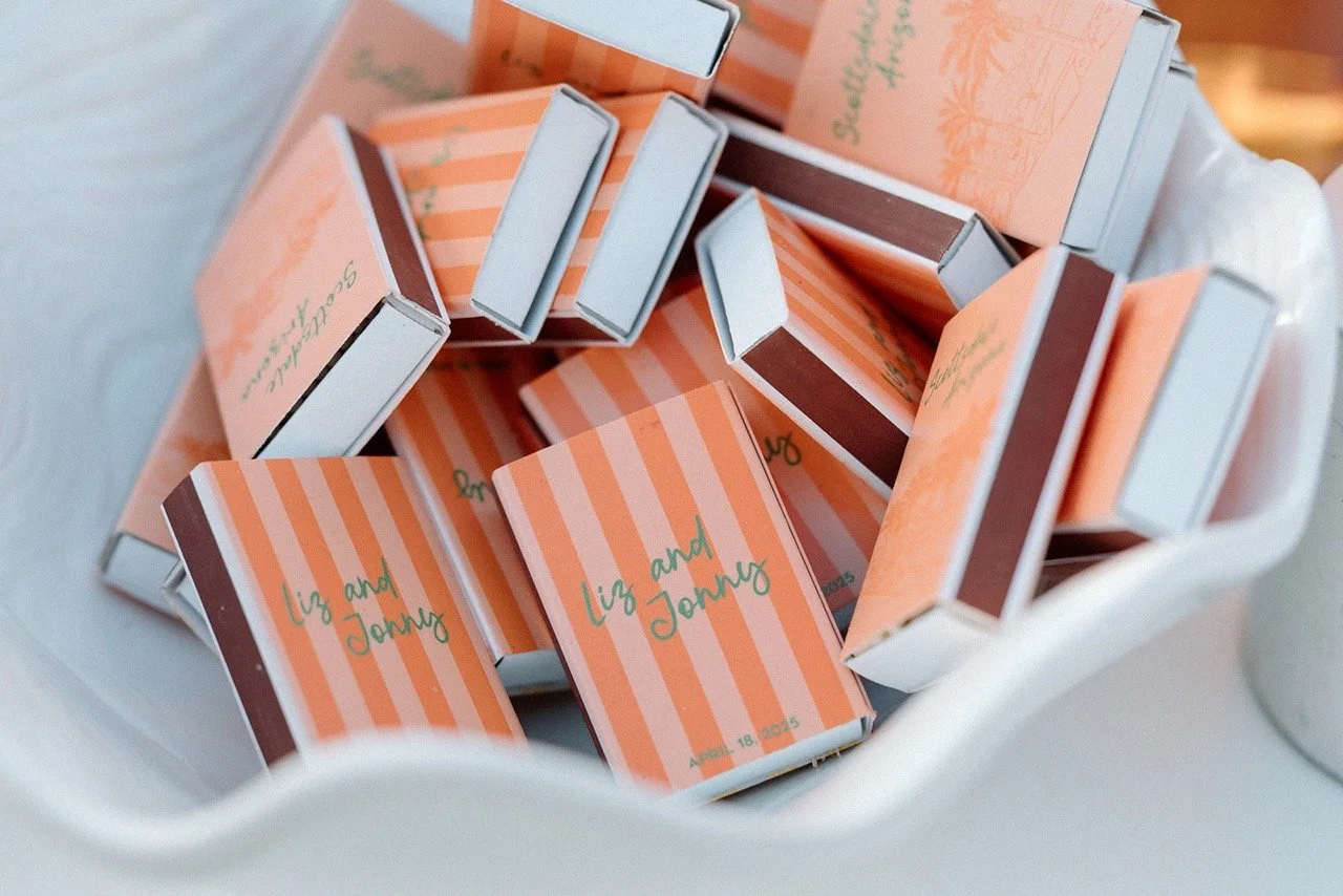 Small boxes with orange and white stripes and green writing that say "Liz and Johnny" inside a white container
