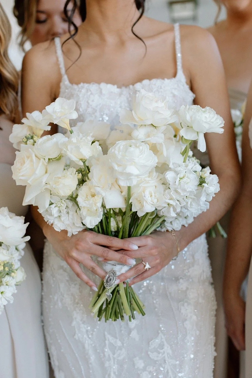 A bride in a white wedding dress holding a large bouquet of white flowers.