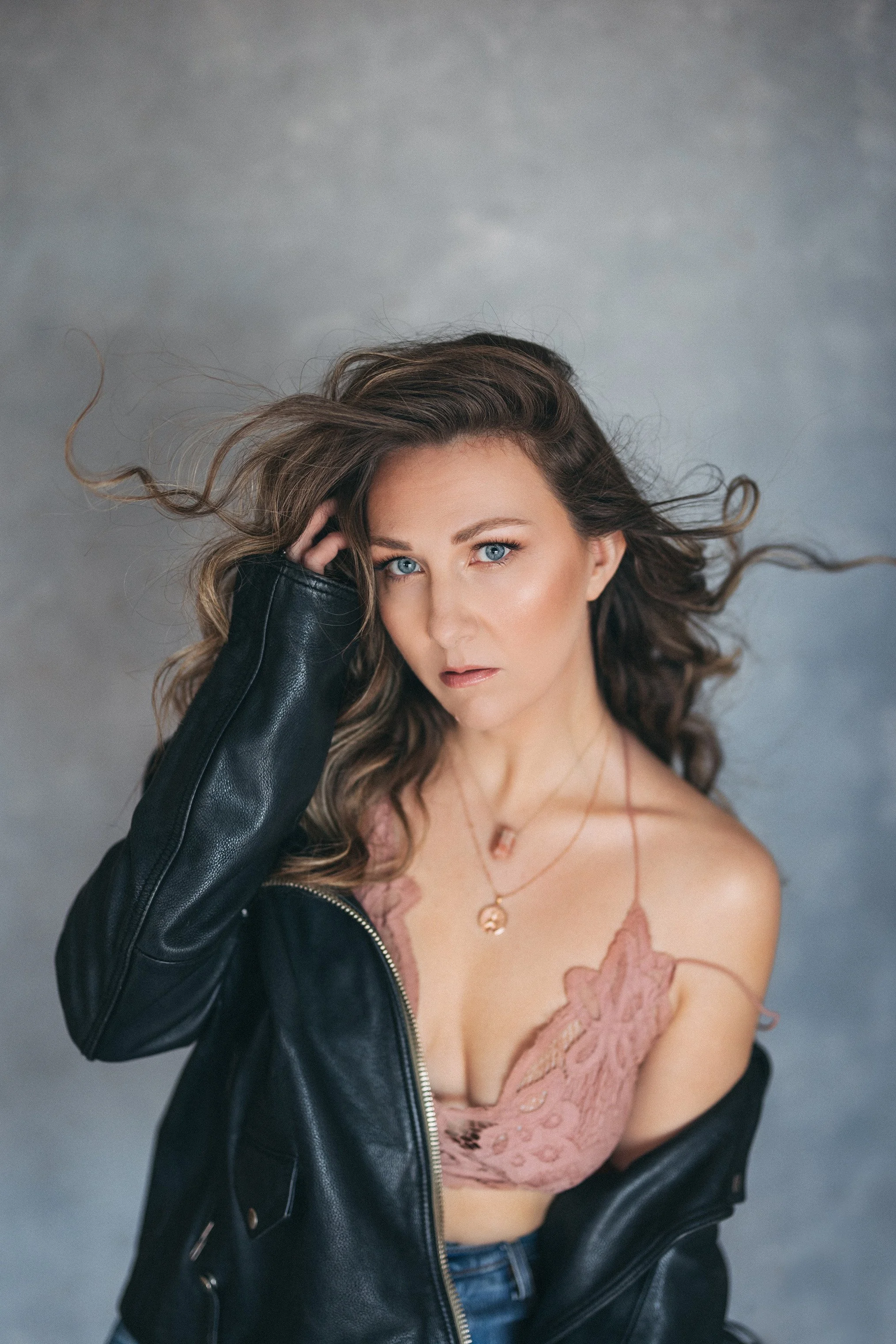 Portrait of dark fantasy romance author, Kaitlyn L. Hill, in a leather jacket and intense eye stare.