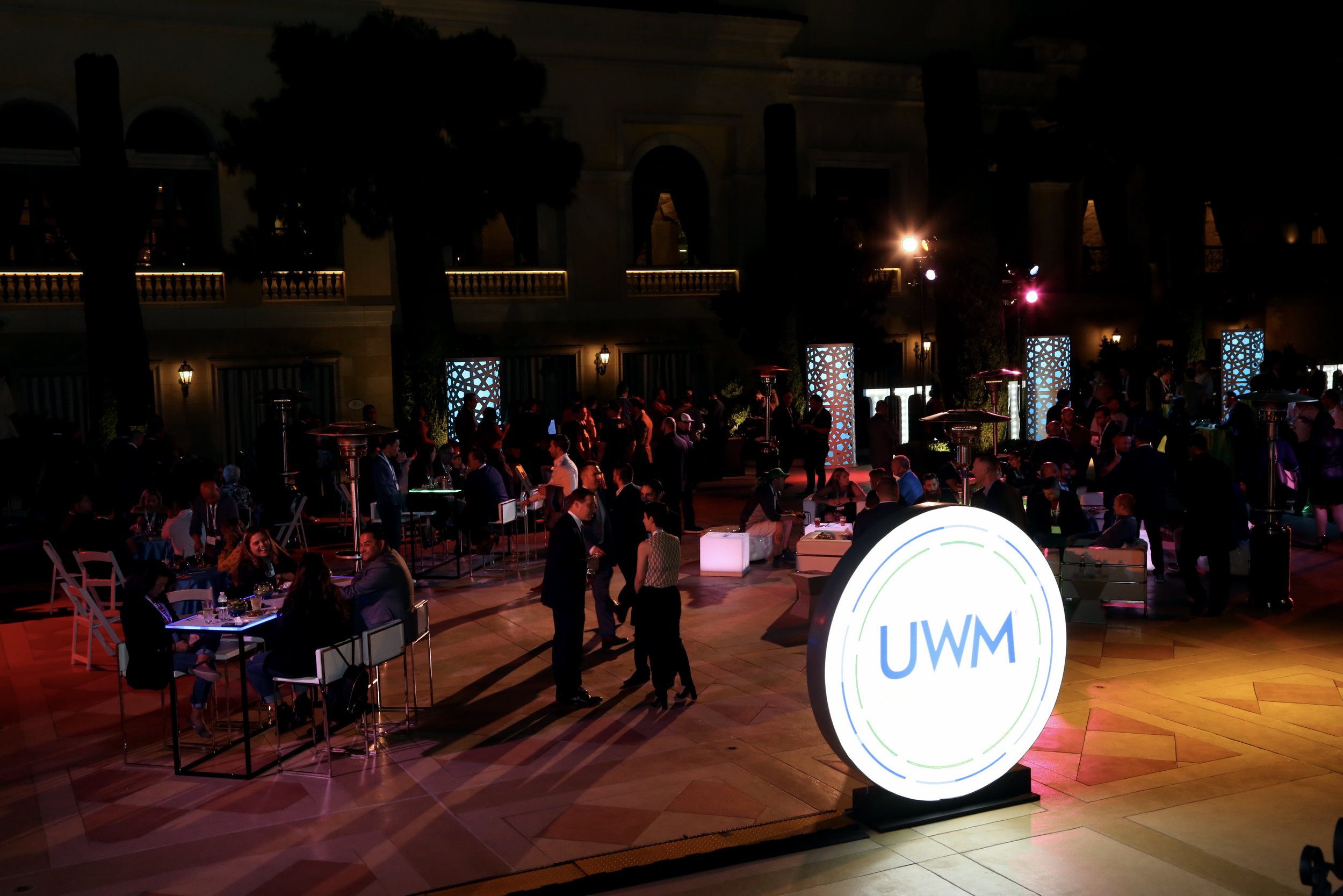 UWM branded illuminated signage at a nighttime outdoor experiential marketing event with attendees.