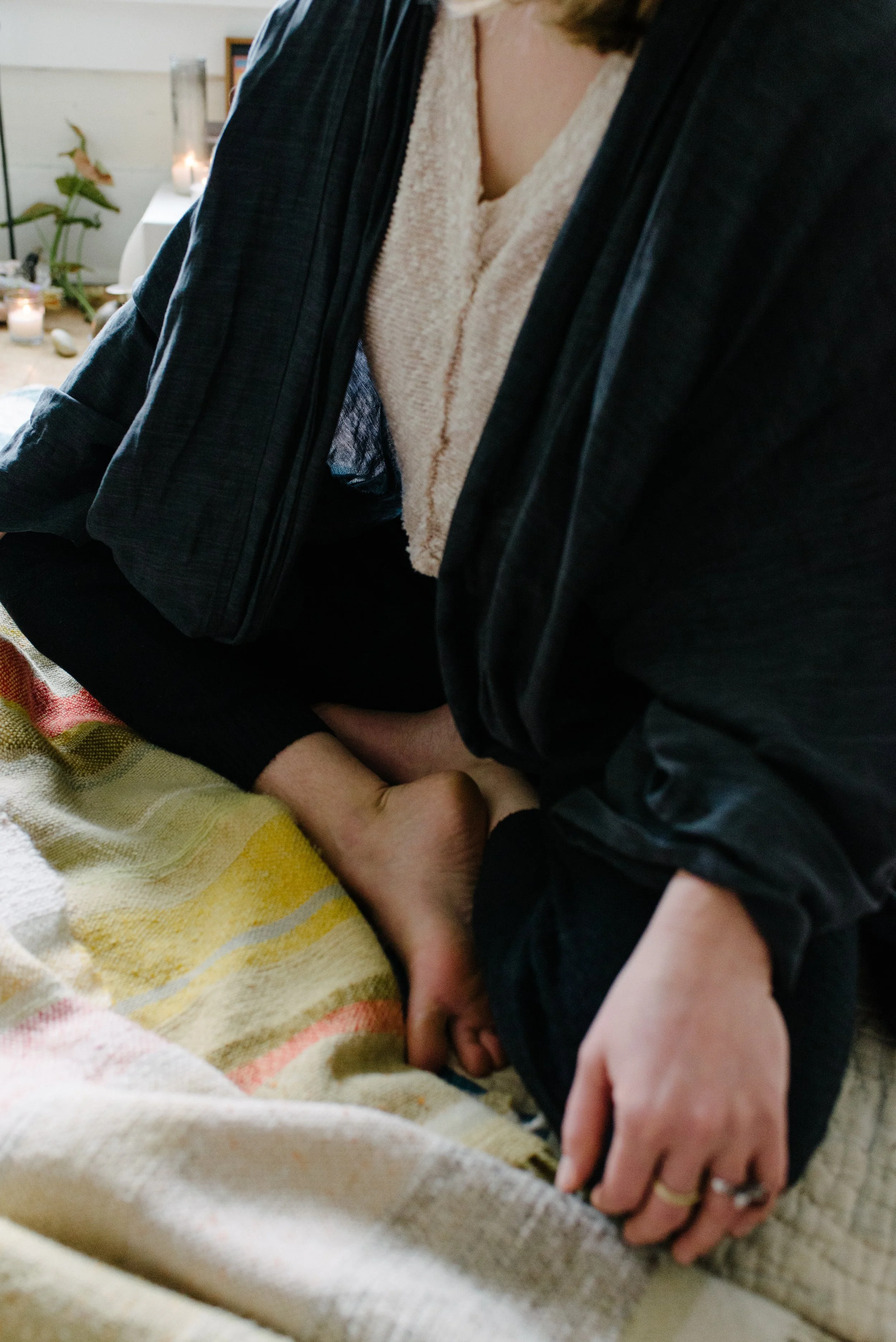 Close-up of a woman resting on a blanket, in a cozy indoor setting with candles and plants in the background. - breathwork coach portland