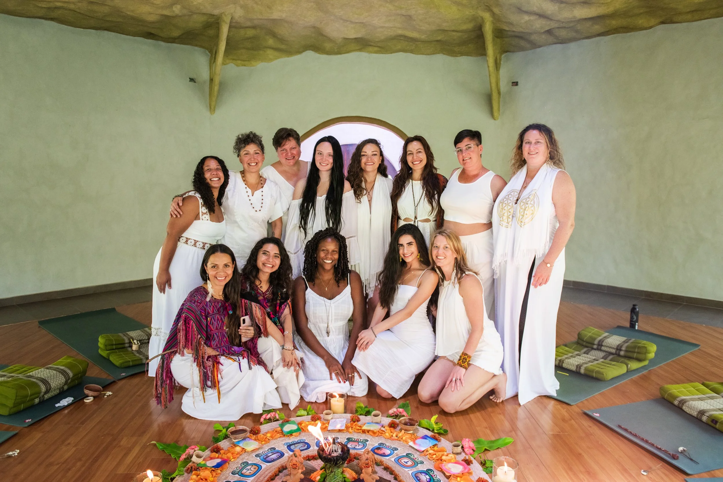 A group of women gathered together indoors for a celebration, with a decorated altar featuring candles, flowers, and ceremonial items in the center. womens retreat facilitator