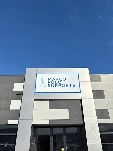 Building with a sign that says 'Marco Polo Supports' and a logo of a hand with three fingers raised.