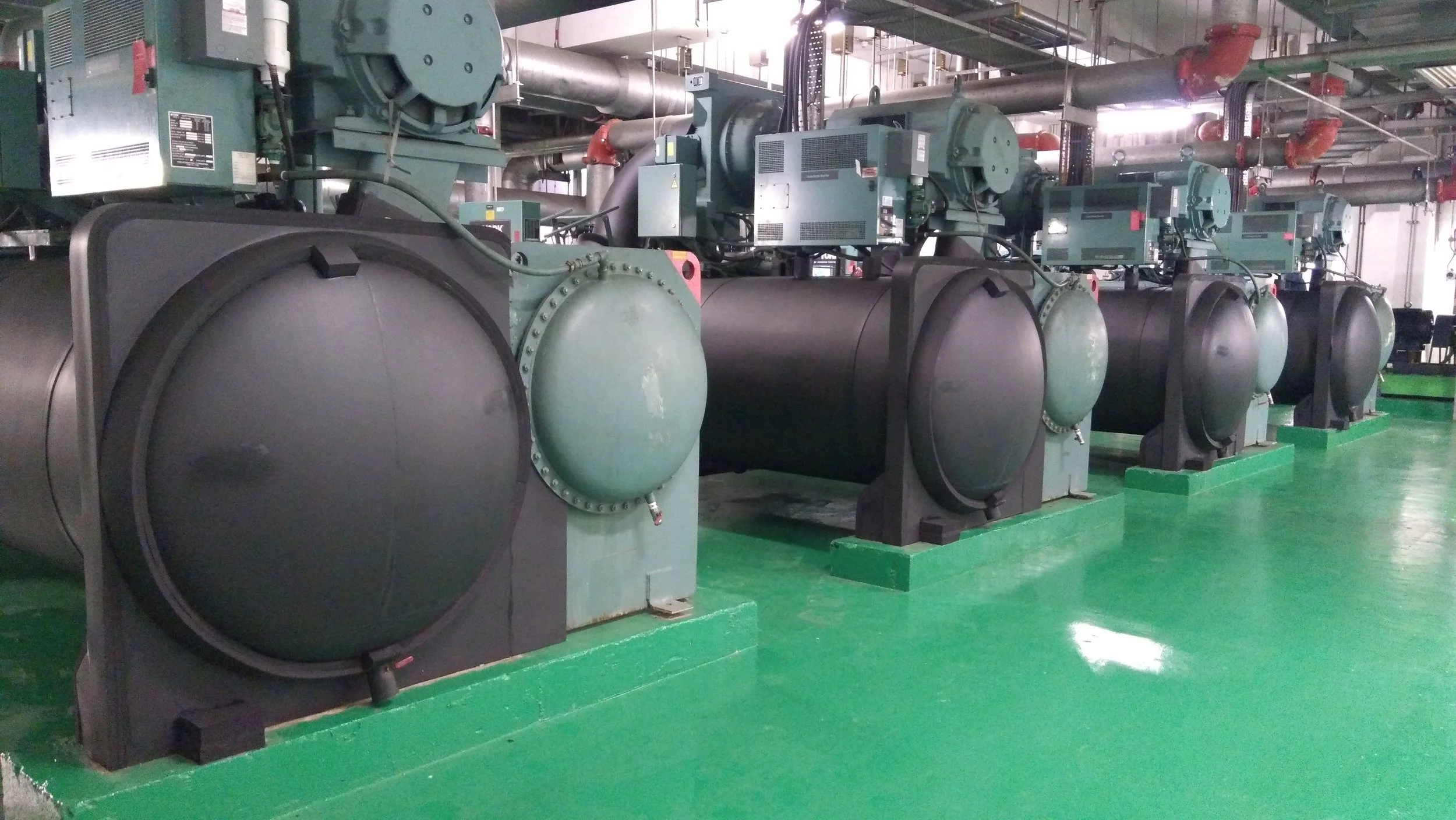 Chilled water plant with chillers, pumps, and cooling towers in commercial building mechanical room